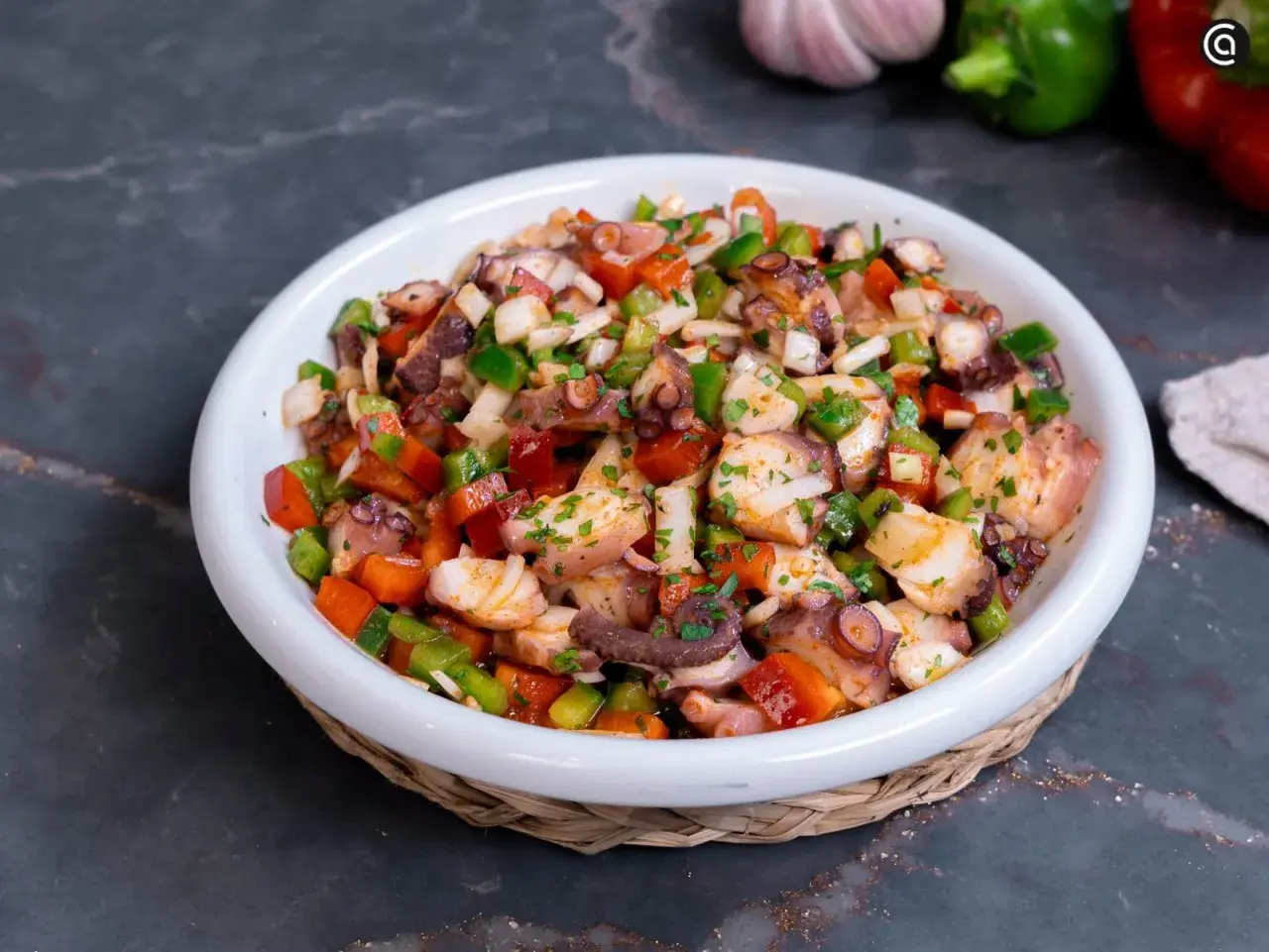 Un refrescante salpicón de pulpo con pimientos, cebolla y perejil, listo para disfrutar.