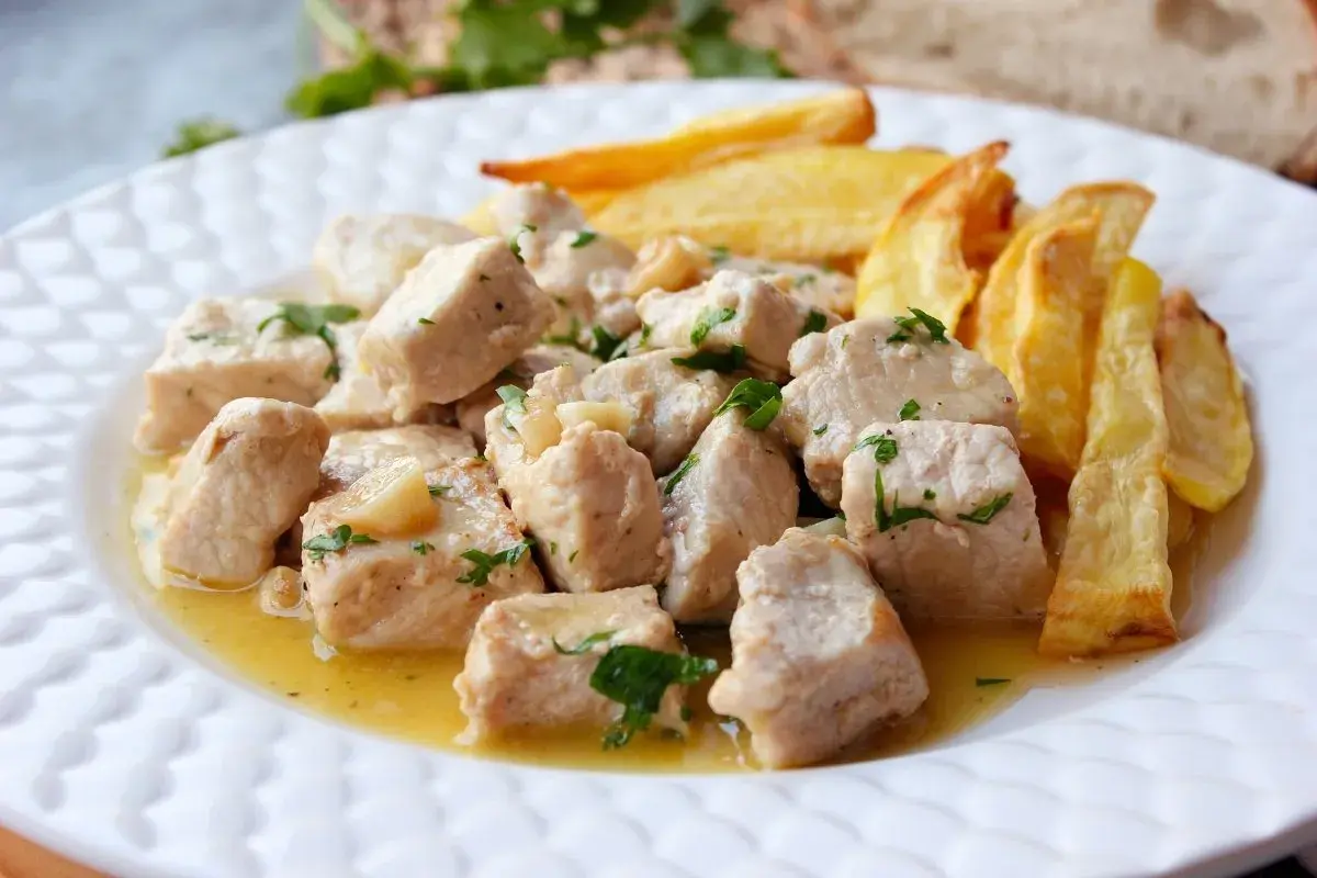 Sabroso lomo al ajillo en trozos, bañado en aceite de oliva con ajo y perejil, acompañado de patatas fritas crujientes.