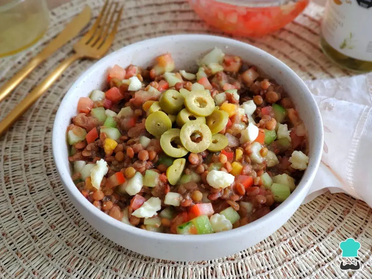 Ensalada de lentejas de bote con tomate, pepino, pimiento y queso fresco, coronada con aceitunas verdes. ¡Un plato fresco y nutritivo!