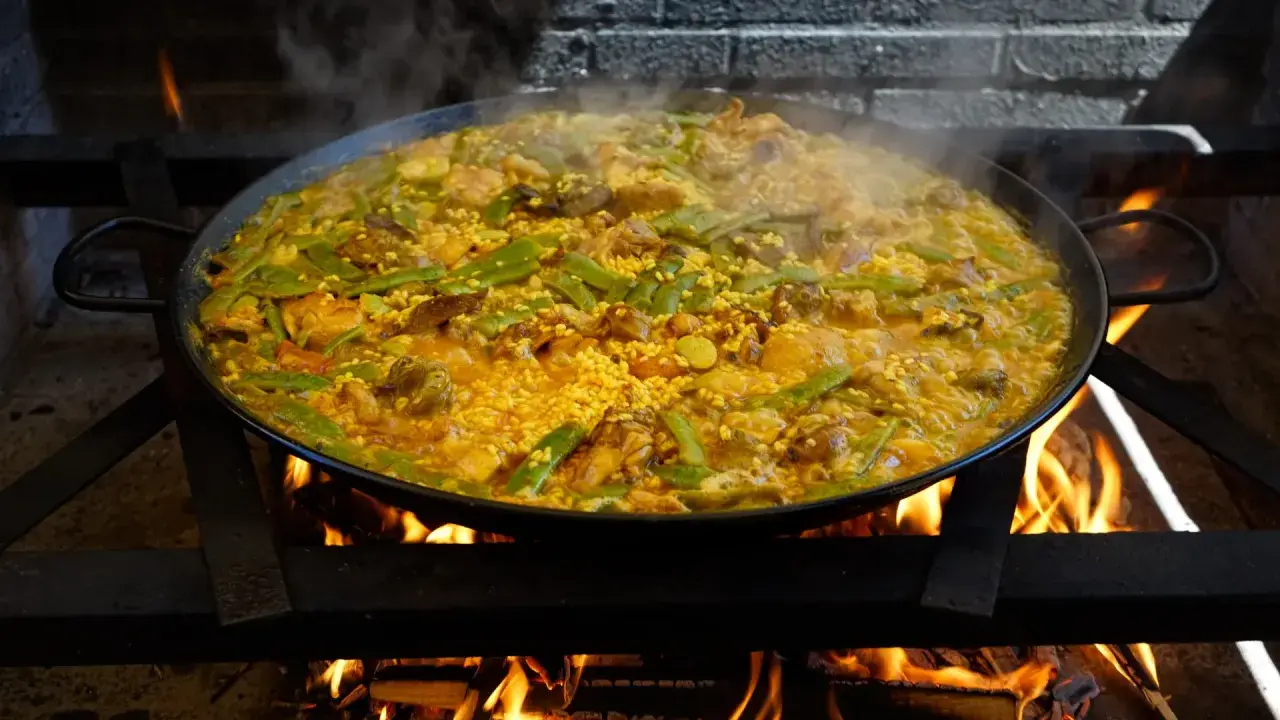 Arroz con carne humeante en paellera sobre fuego vivo. Judías verdes y trozos de carne se mezclan con el arroz dorado.