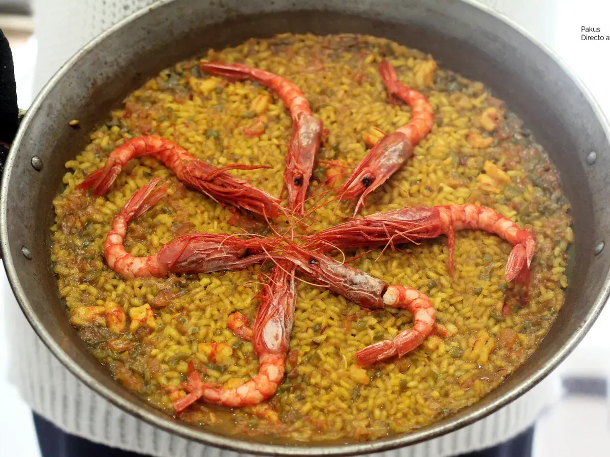 Arroz con carabineros, un plato de paella con gambas rojas grandes dispuestas en círculo sobre el arroz amarillo.