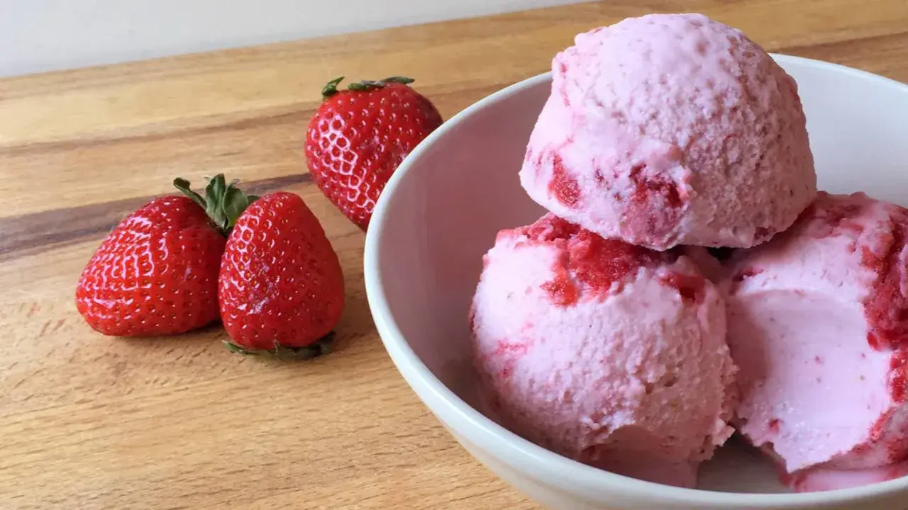Bol con helado de fresa cremoso y trozos de fruta fresca.