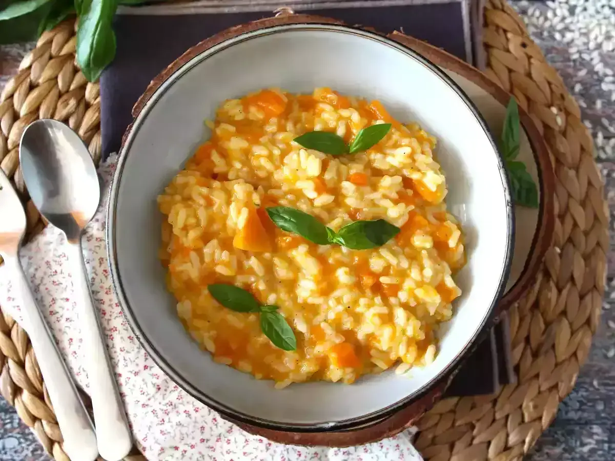 Cremoso risotto de calabaza, adornado con hojas de albahaca fresca, servido en un cuenco rústico.