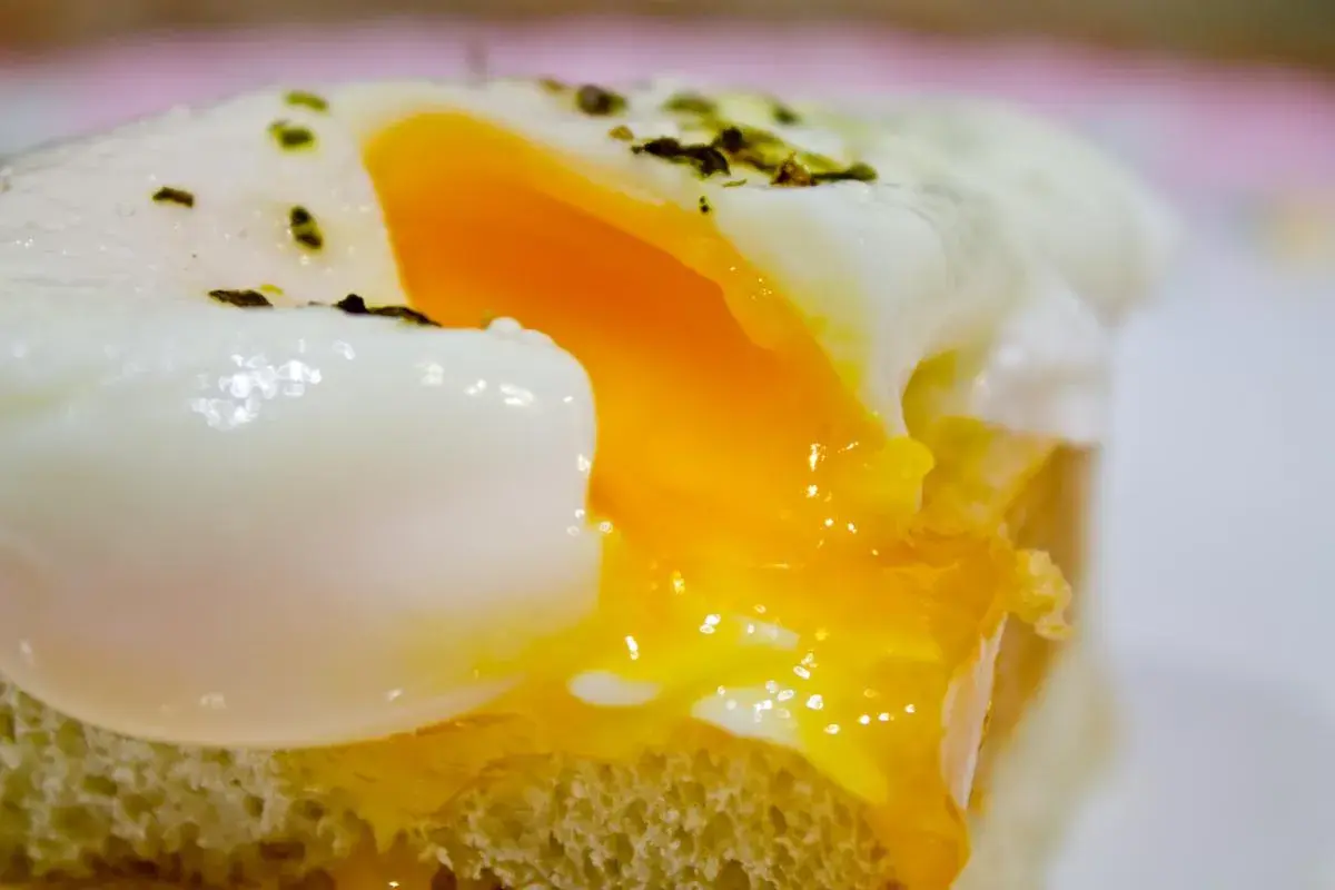 Un huevo poche microondas perfecto, con la clara cuajada y la yema líquida, servido sobre una tostada.