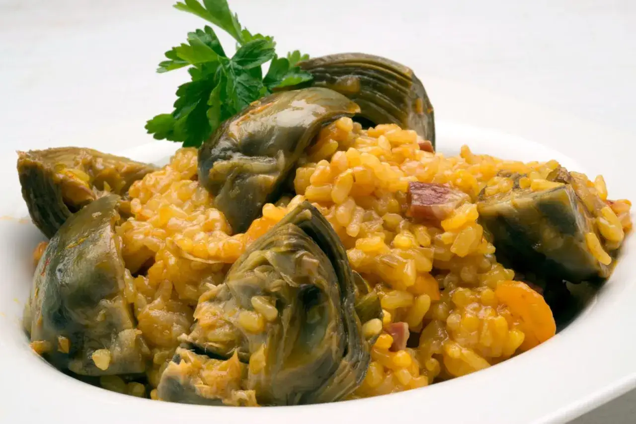 Un delicioso arroz con alcachofas, adornado con perejil fresco.