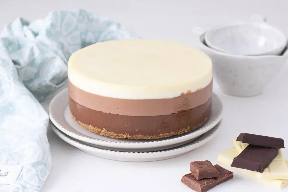 Deliciosa tarta de 3 chocolates, con capas de chocolate blanco, con leche y negro, sobre una base crujiente.