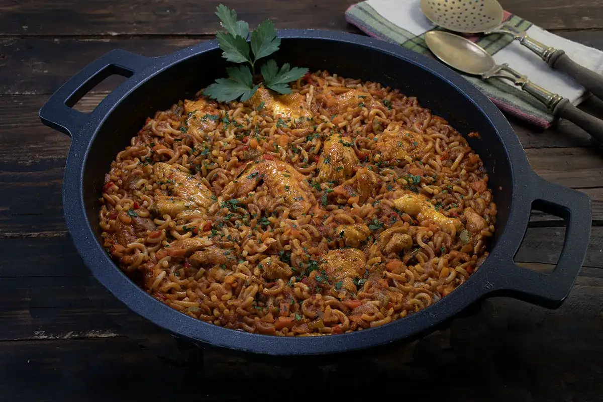 Fideu&agrave; de pollo servida en paellera, con trozos de pollo dorado y fideos finos en salsa rojiza, decorada con perejil fresco.