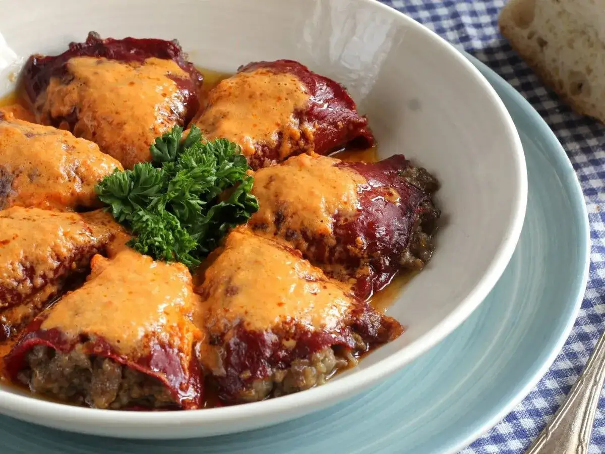 Pimientos rellenos de carne, cubiertos con una cremosa salsa y decorados con perejil fresco. Un plato casero delicioso.