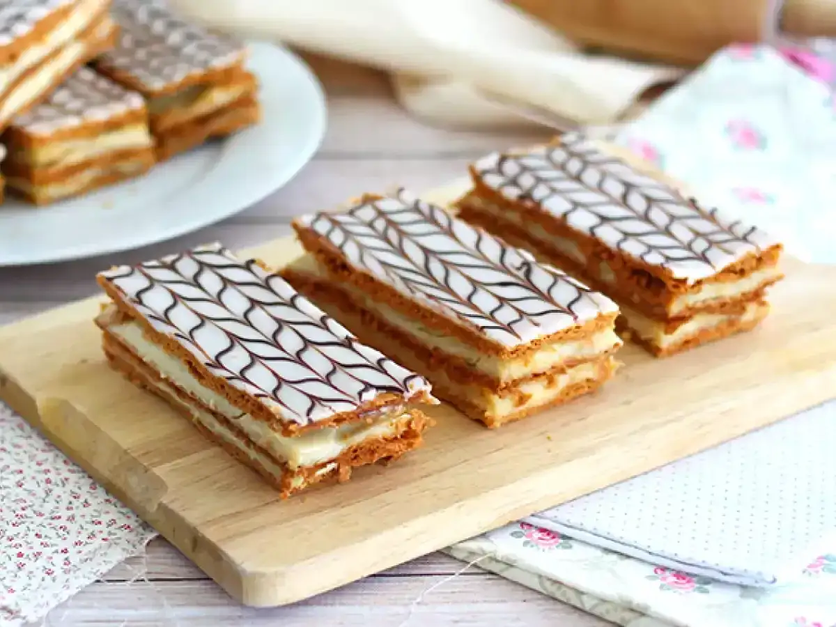 Tres deliciosos milhojas de crema, con capas crujientes y un glaseado blanco decorado con chocolate, listos para disfrutar.