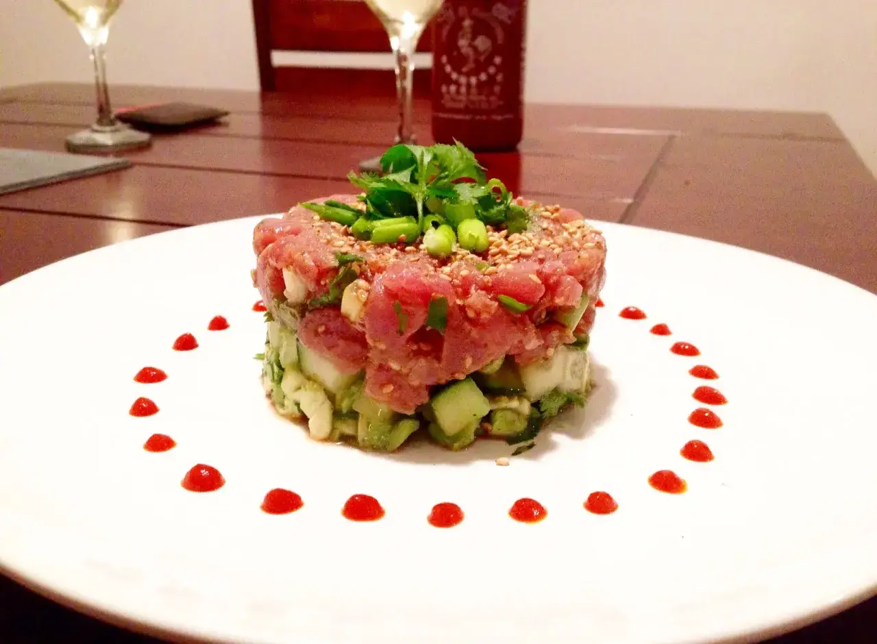 Delicioso tartar de at&uacute;n fresco con aguacate y pepino, decorado con semillas de s&eacute;samo y un toque picante.