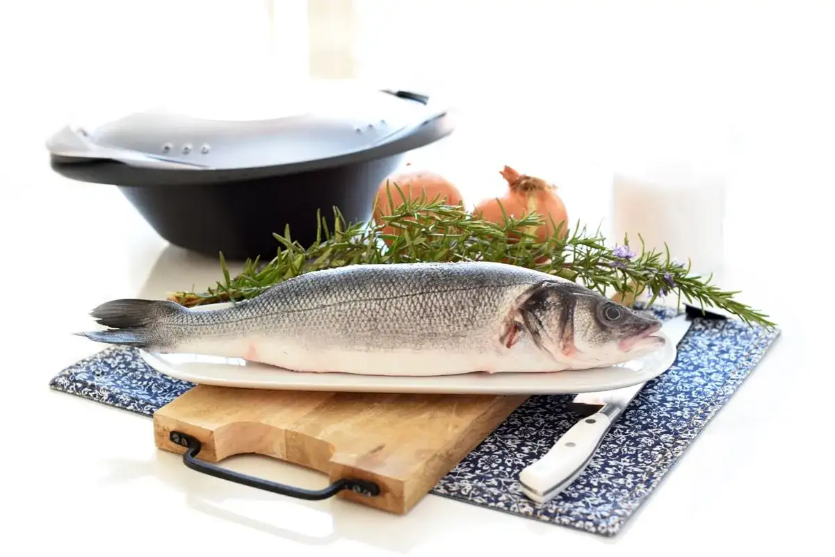 Lubina a la sal lista para cocinar, con romero, cebolla y sal.