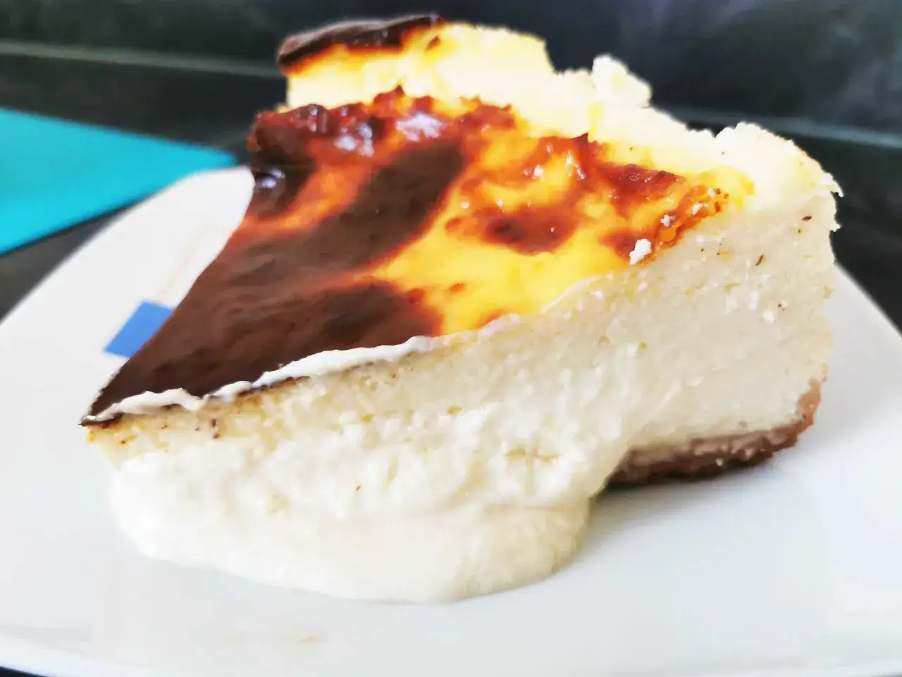 Una porci&oacute;n de tarta de queso al horno con la parte superior dorada y cremosa.