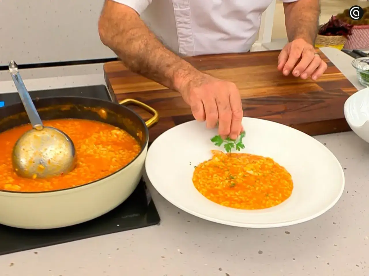 Chef decora un plato de cremoso risotto de gambas con perejil fresco.