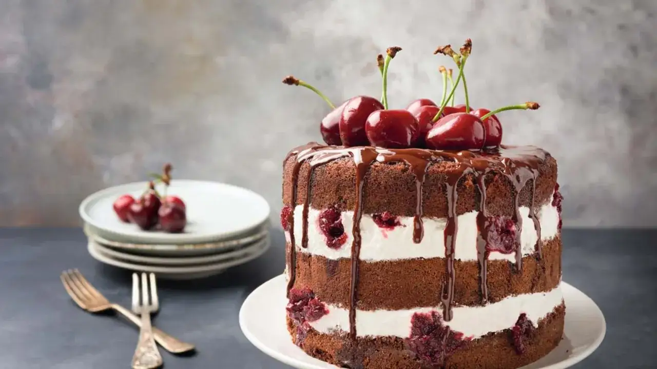 Deliciosa tarta Selva Negra con capas de bizcocho de chocolate, crema y cerezas, cubierta de chocolate derretido y coronada con cerezas frescas.