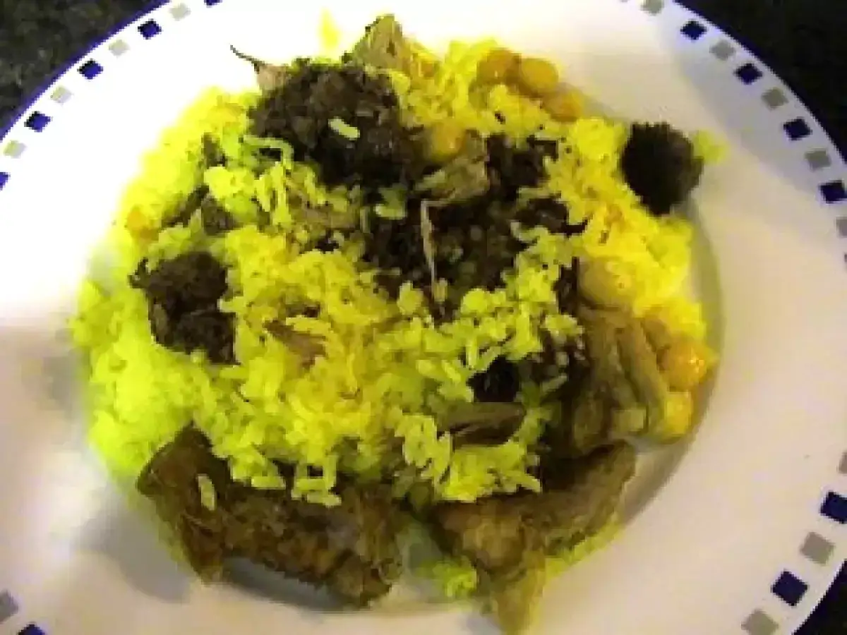 Arroz amarillo con trozos de carne oscura y garbanzos, un plato sabroso de arroz con carne.
