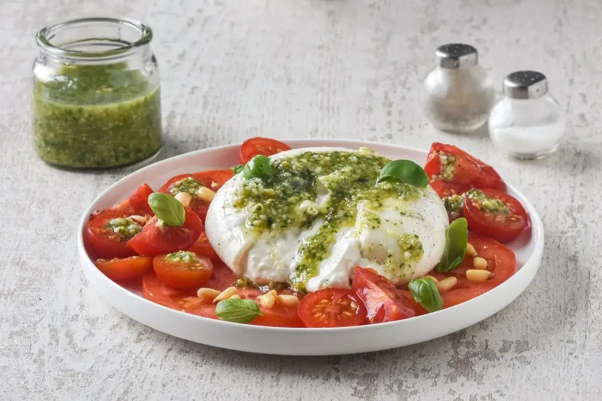 Deliciosa ensalada de burrata y pesto, con tomates frescos, pi&ntilde;ones y albahaca. Un plato ligero y lleno de sabor.