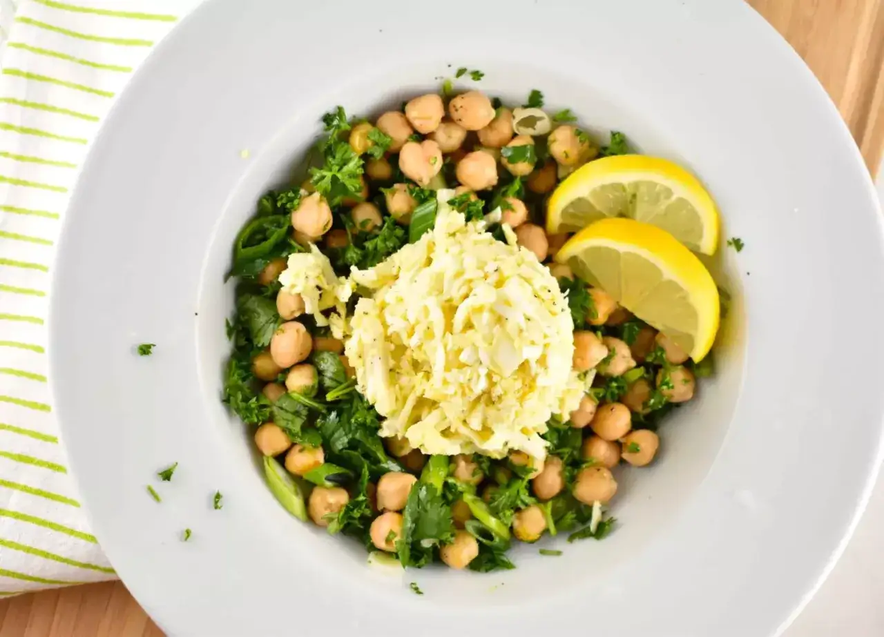 Ensalada de garbanzos fresca con huevo picado, perejil y rodajas de limón.