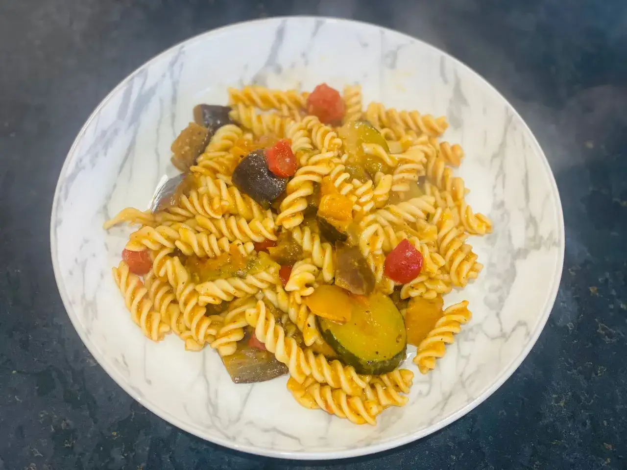 Pasta fusilli con trozos de berenjena, calabac&iacute;n y tomate. Un plato de pasta con verduras vibrante y apetitoso.