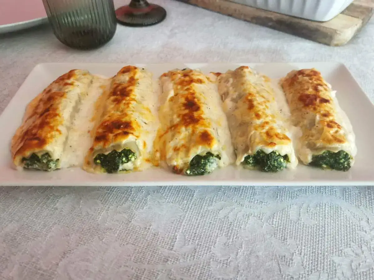 Canelones de espinacas gratinados con bechamel cremosa, listos para disfrutar en una cena especial.