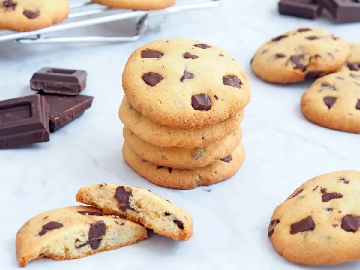 Galletas de chocolate reci&eacute;n horneadas, perfectas para tu pr&oacute;xima receta de galletas chocolate. Trozos de chocolate negro y una rejilla de enfriamiento al fondo.