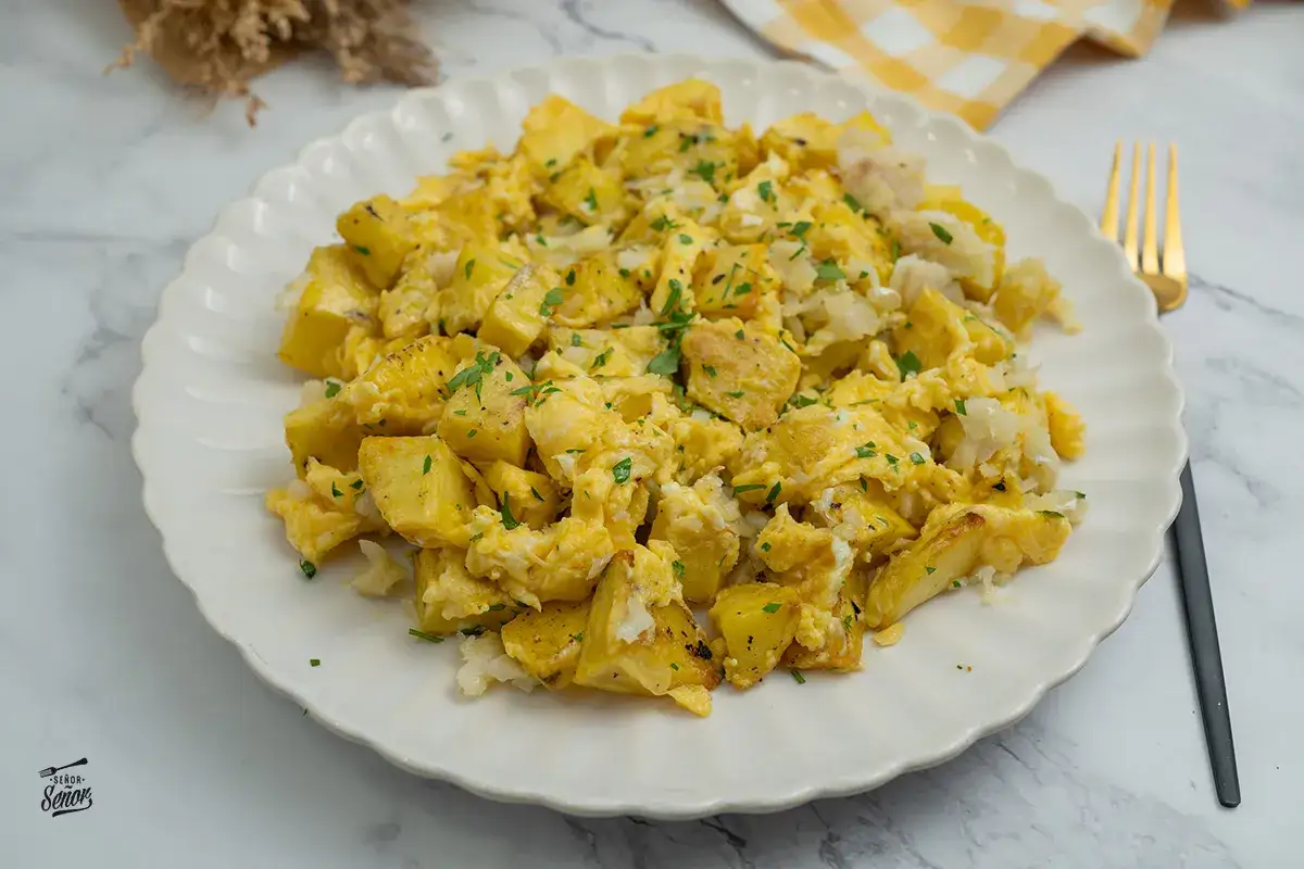 Un delicioso revuelto de bacalao con patatas, espolvoreado con perejil fresco. Un plato casero perfecto para cualquier momento del d&iacute;a.