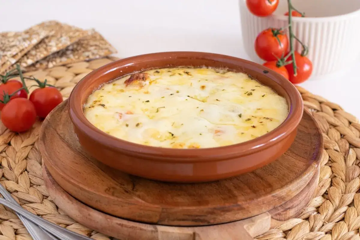 Un cremoso provolone al horno, burbujeante y dorado, servido con tomates cherry y galletas crujientes.