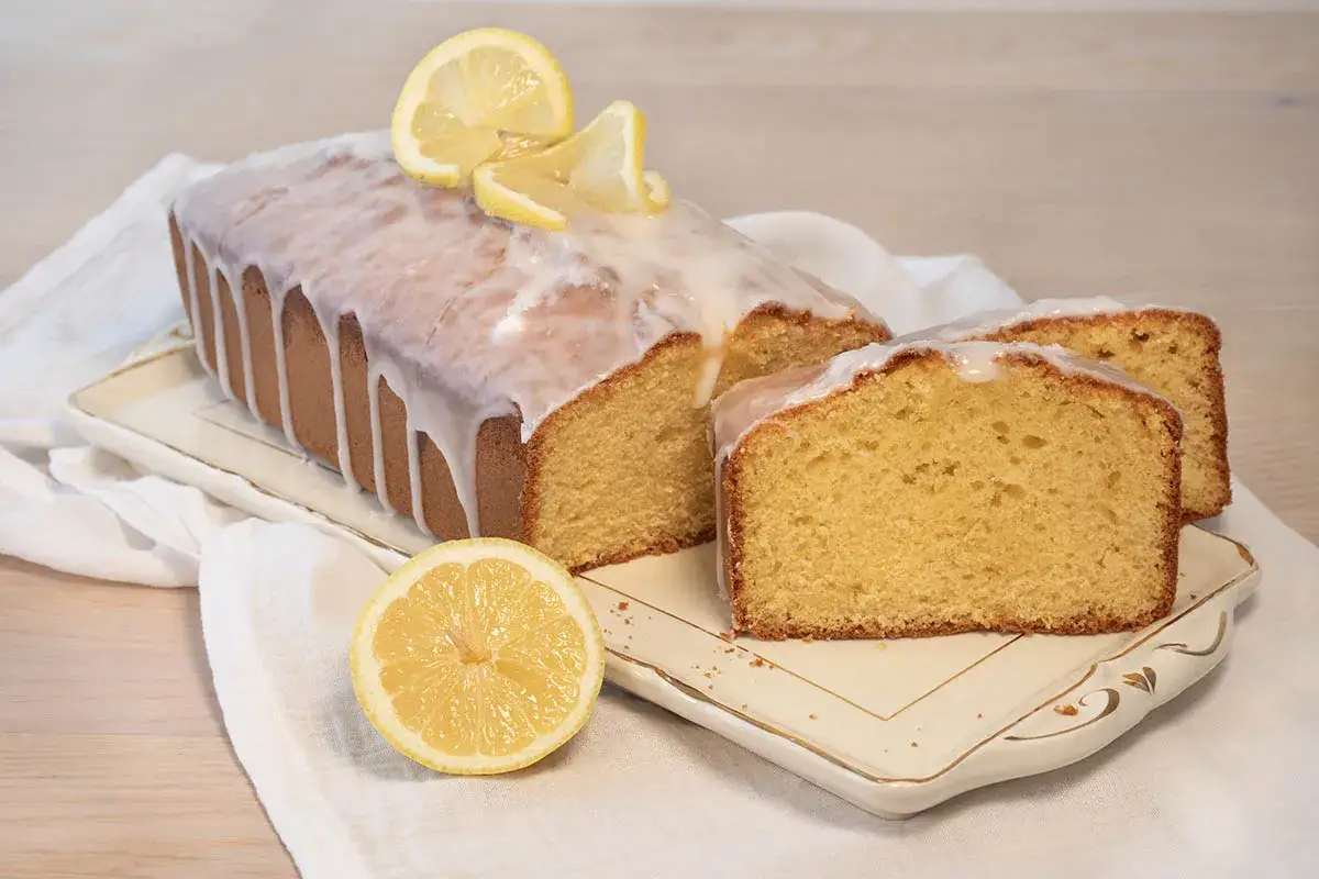 Un delicioso bizcocho de lim&oacute;n cubierto de glaseado blanco y decorado con rodajas de lim&oacute;n.