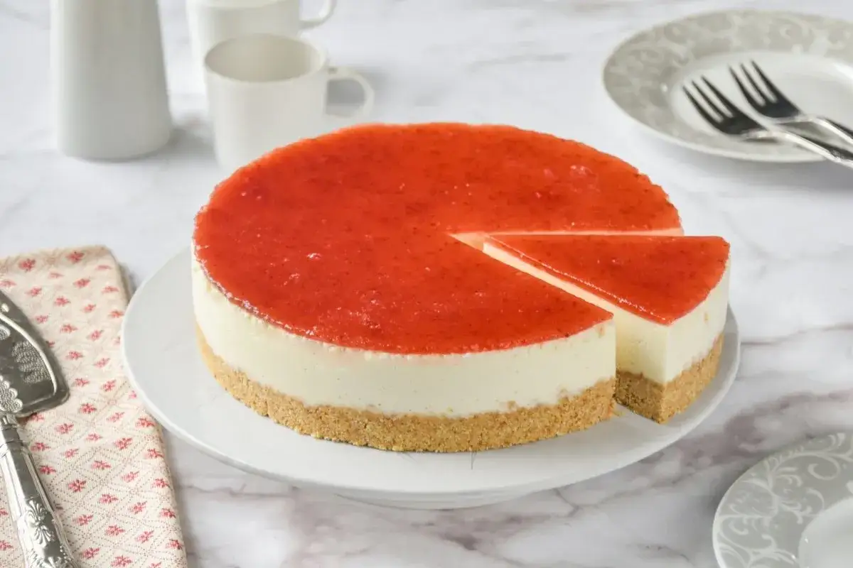 Deliciosa tarta de queso fr&iacute;a con cobertura de fresa, lista para servir.