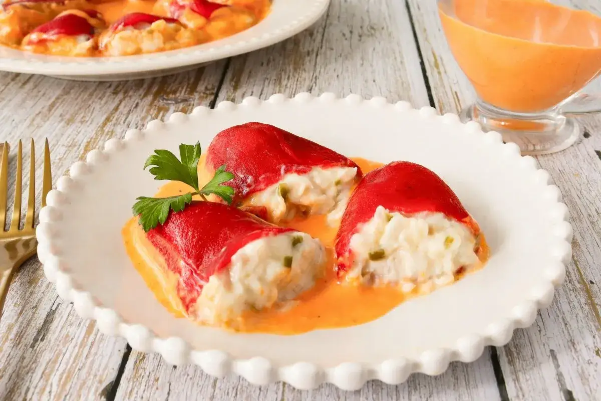 Deliciosos pimientos rellenos de bacalao, cubiertos con una cremosa salsa.