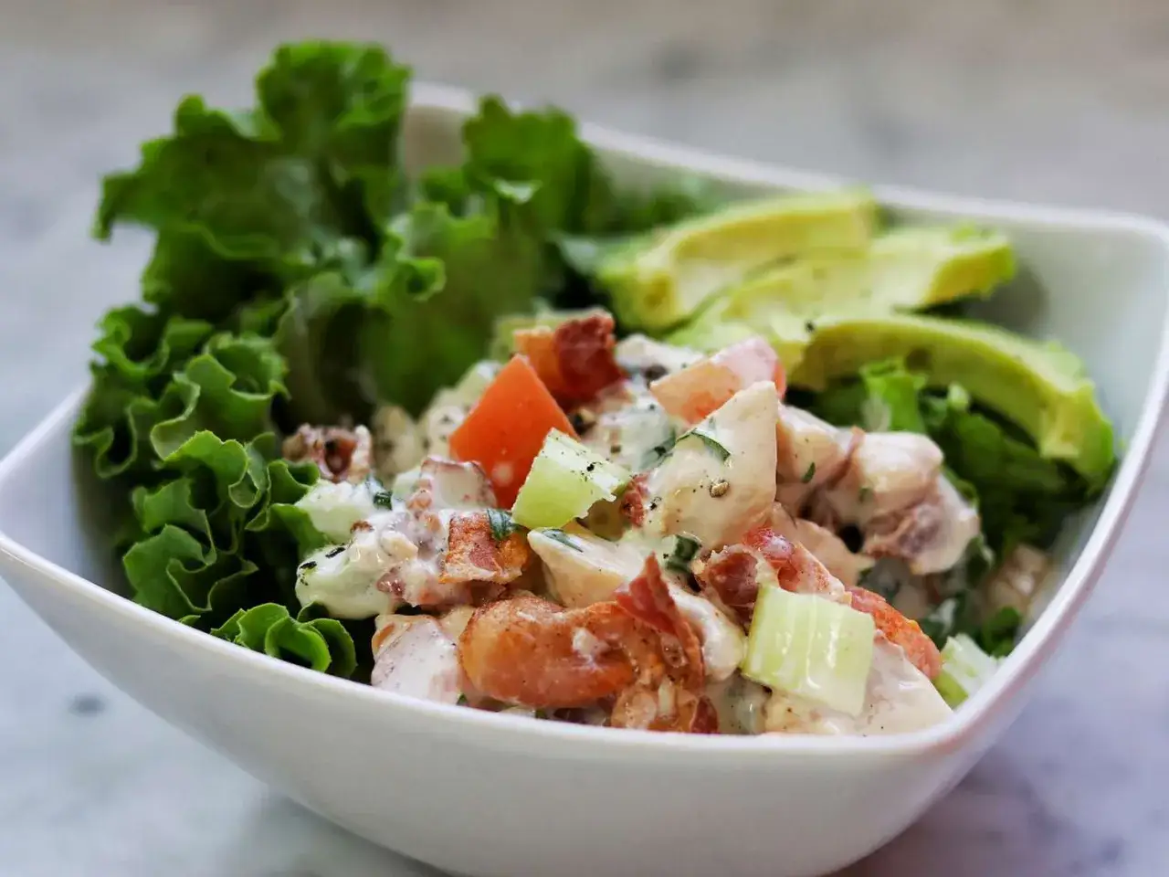 Ensalada de pollo y lechuga cremosa con aguacate y tocino crujiente.