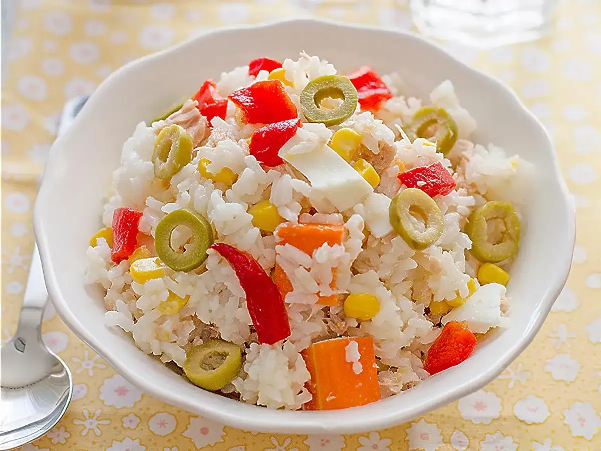 Ensalada de arroz con ingredientes coloridos: pimiento rojo, aceitunas, ma&iacute;z y huevo duro.