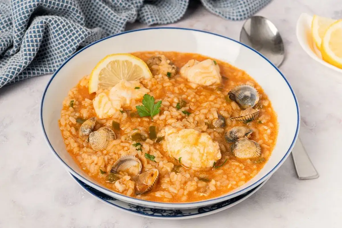 Un sabroso arroz con pescado y mariscos, adornado con lim&oacute;n y perejil.