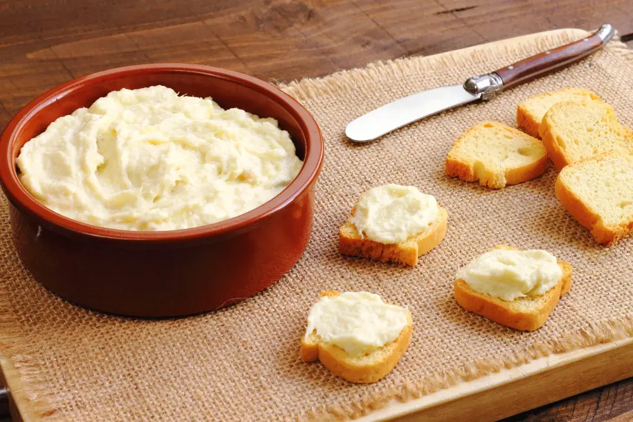 Deliciosa brandada de bacalao cremosa servida en una cazuela de barro, con tostas de pan listas para untar.