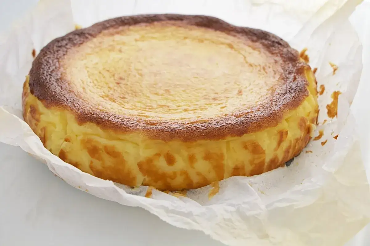 Tarta de queso la Vi&ntilde;a, dorada y cremosa, envuelta en papel de horno. Su corteza caramelizada promete un interior irresistible.