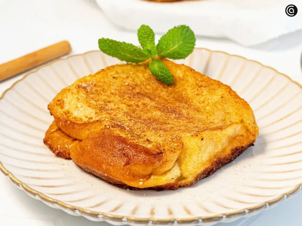 Torrijas de horchata doradas y crujientes, espolvoreadas con az&uacute;car y canela, coronadas con menta fresca.