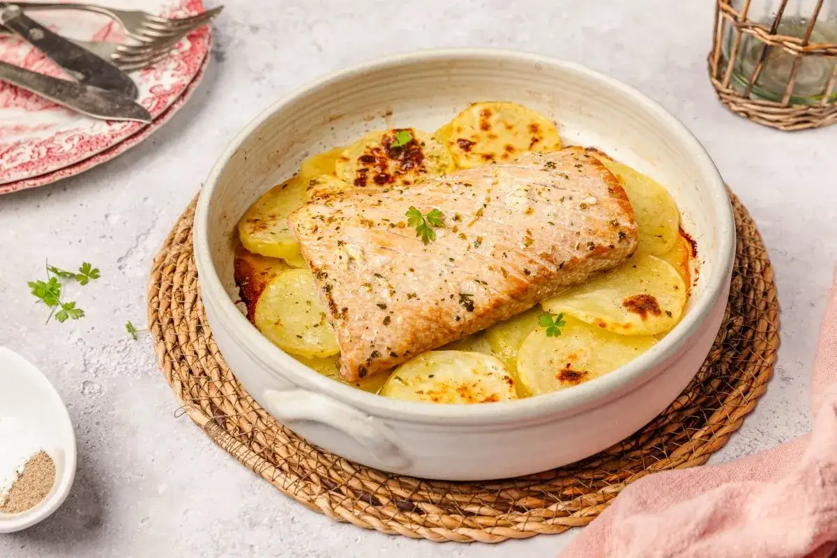 Deliciosa ventresca al horno sobre patatas doradas, un plato casero listo para disfrutar.