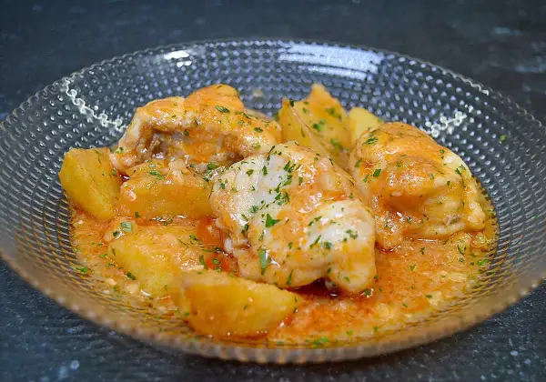 Rape en salsa marinera con patatas, adornado con perejil picado.