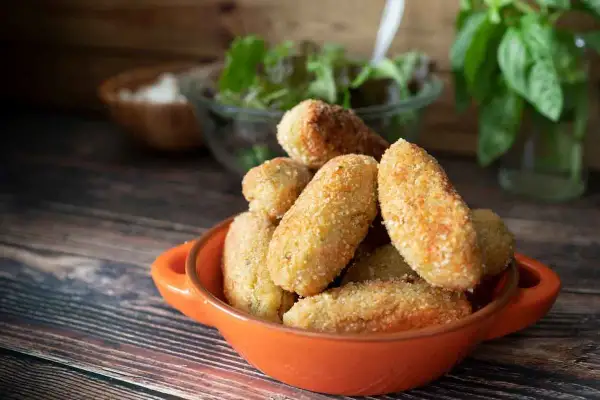 Croquetas de jamón doradas y crujientes en un cuenco naranja, listas para disfrutar.