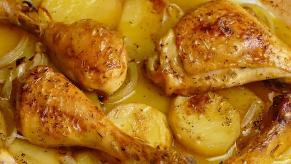 Pollo al horno con patatas y cebolla, dorado y jugoso, con hierbas aromáticas. Un plato casero irresistible.