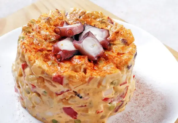 Ensaladilla de pulpo cremosa, con trozos de pulpo tierno y pimentón espolvoreado.