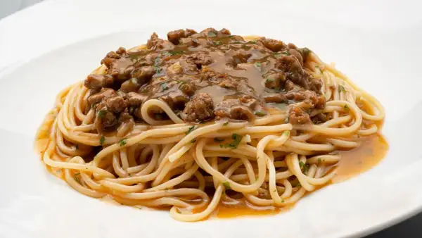Un plato de espaguetis con una generosa porción de macarrones con carne picada, cubiertos con una sabrosa salsa.