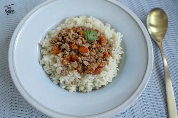 Un plato de arroz blanco cubierto con una sabrosa mezcla de arroz con carne picada, tomates y pimientos.
