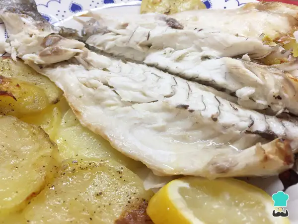 Lubina al horno jugosa y tierna, servida con patatas asadas y rodajas de limón. Un plato delicioso y saludable.