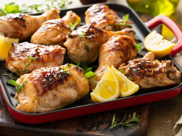 Muslos de pollo dorados y jugosos, asados a la parrilla con hierbas frescas y gajos de limón. ¡Un festín para los sentidos!