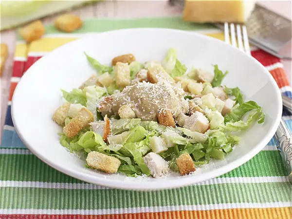 Ensalada César con pollo, lechuga, crutones y queso rallado. Los ensalada cesar ingredientes se ven frescos y apetitosos.