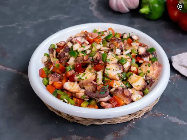 Un refrescante salpicón de pulpo con pimientos, cebolla y perejil, listo para disfrutar.