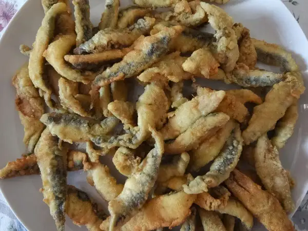 Un plato lleno de boquerones a la andaluza, crujientes y dorados, listos para disfrutar.