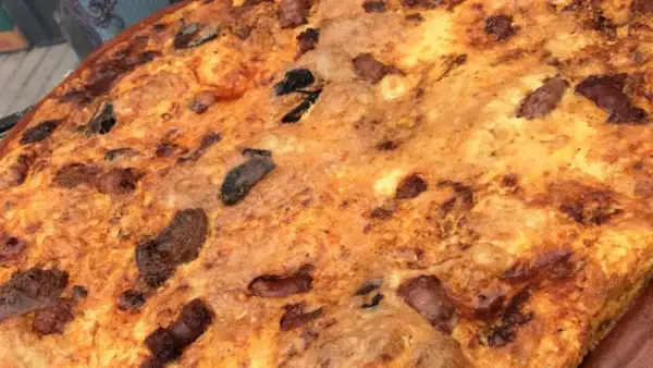 Arroz con costra dorado y crujiente, con trozos de carne y aceitunas negras incrustados.