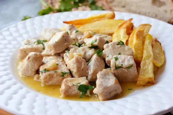 Sabroso lomo al ajillo en trozos, bañado en aceite de oliva con ajo y perejil, acompañado de patatas fritas crujientes.