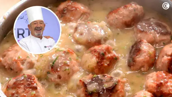 Chef sonriente presenta un plato de albóndigas con patatas en salsa cremosa, decorado con perejil picado.